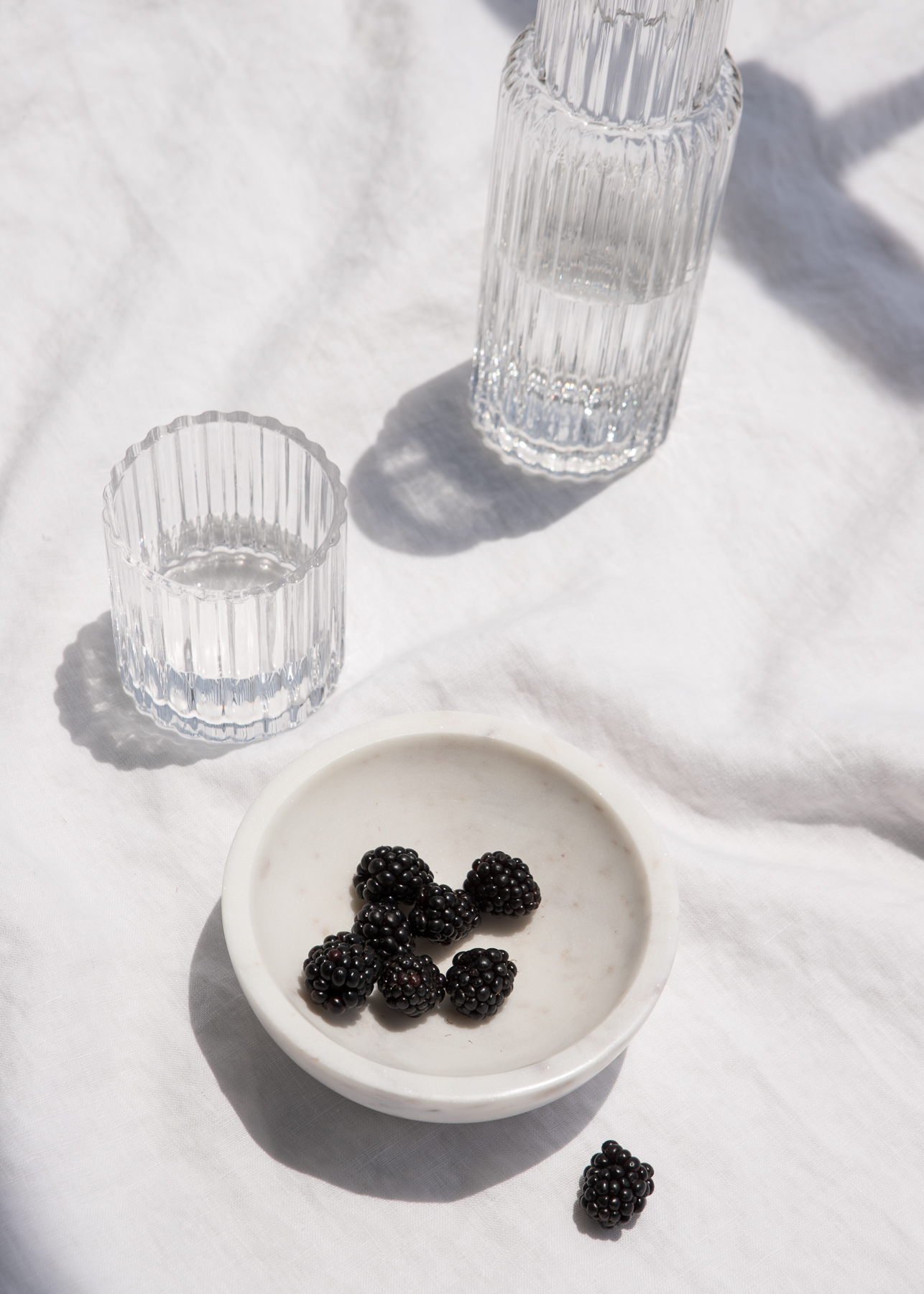 2 glasses with a bowl of berries set on a white table cloth