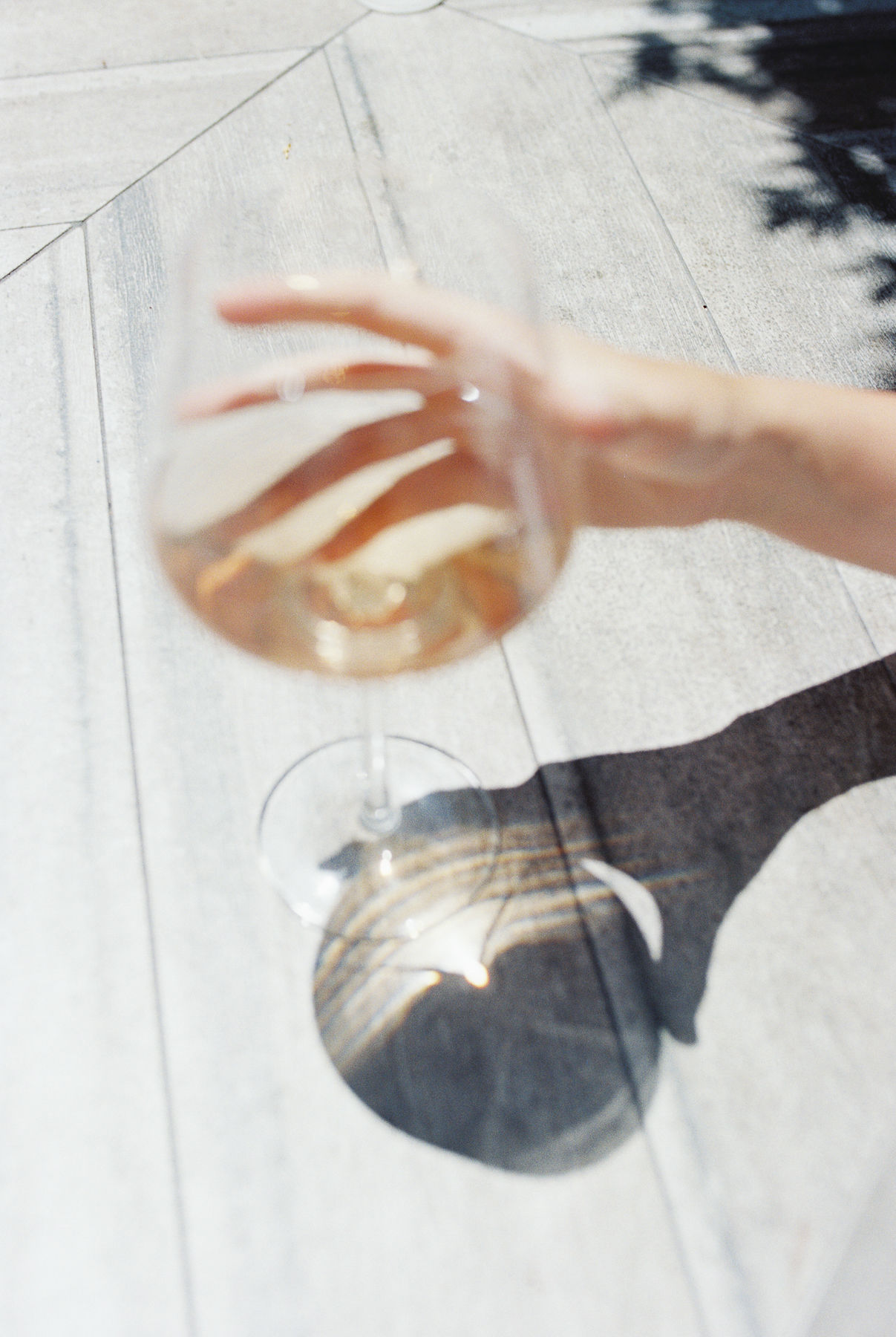 female hand holding glass of white wine with a wooden background