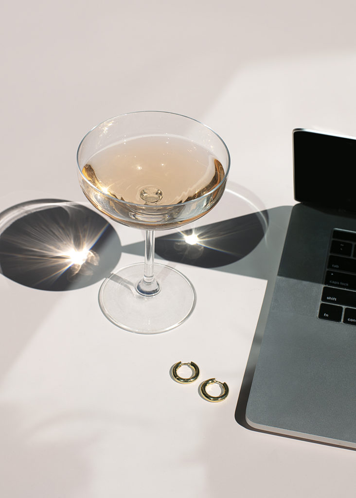 champagne glass, laptop on a soft pink background